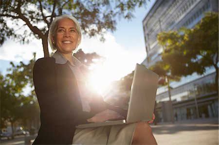 simsearch:649-07280768,k - Businesswoman sitting outside using laptop Photographie de stock - Premium Libres de Droits, Code: 649-07280769