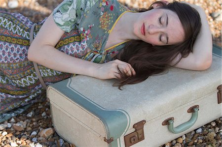 Portrait of young woman lying with suitcase on beach, Whitstable, Kent, UK Stock Photo - Premium Royalty-Free, Code: 649-07280794