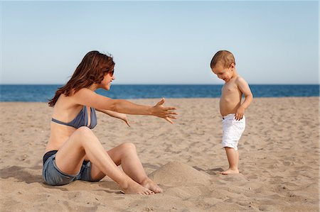 sit beach - Pregnant woman sitting on beach with arms open to toddler Foto de stock - Sin royalties Premium, Código: 649-07436392