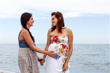 pregnant hispanic mom - Woman with hand on pregnant friend's stomach Stock Photo - Premium Royalty-Free, Code: 649-07436416