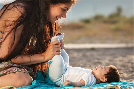 summer beach kids - Mother looking down at baby lying on rug Stock Photo - Premium Royalty-Free, Code: 649-07436431