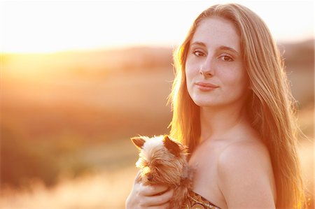 simsearch:649-07437909,k - Teenager standing in field at dusk holding domestic dog Fotografie stock - Premium Royalty-Free, Codice: 649-07436499