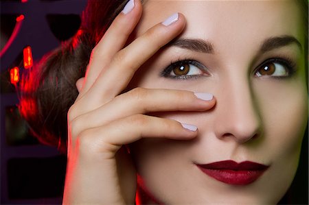 eyes looking away - Close up portrait of smiling young woman with hand on face Stock Photo - Premium Royalty-Free, Code: 649-07436641