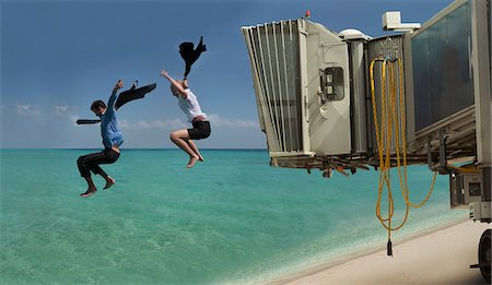 Couple jumping out of airport bridge onto seashore Stock Photo - Premium Royalty-Free, Code: 649-07436746