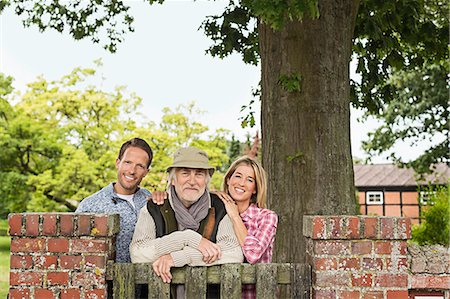 simsearch:649-07436769,k - Portrait of senior man with mid adult couple leaning on gate Fotografie stock - Premium Royalty-Free, Codice: 649-07436824
