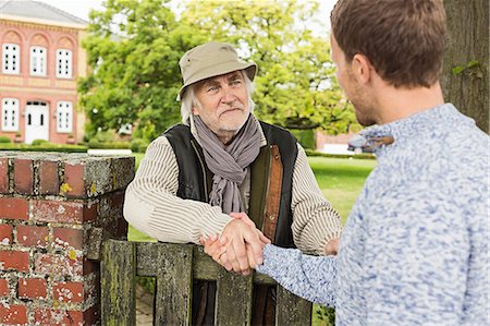 simsearch:649-07436826,k - Senior man and mid adult man shaking hands over gate Stock Photo - Premium Royalty-Free, Code: 649-07436827