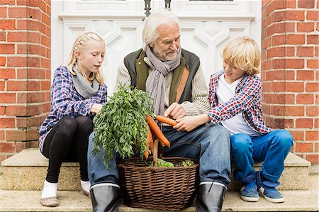 people, house exterior - Grandfather sitting with grandchildren on doorstep with carrots Stock Photo - Premium Royalty-Free, Code: 649-07436847