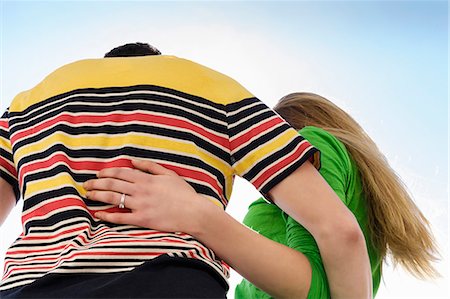 engagement ring - Couple with arms around each other against sky, low angle Stock Photo - Premium Royalty-Free, Code: 649-07436934