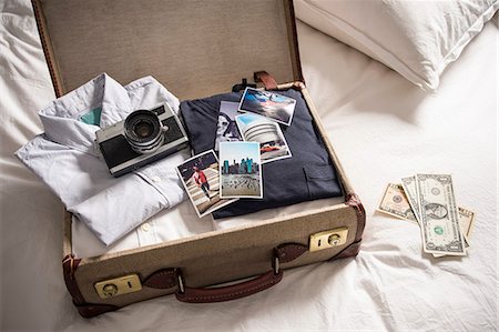 Open suitcase on bed with camera and photographs Photographie de stock - Premium Libres de Droits, Code: 649-07437011