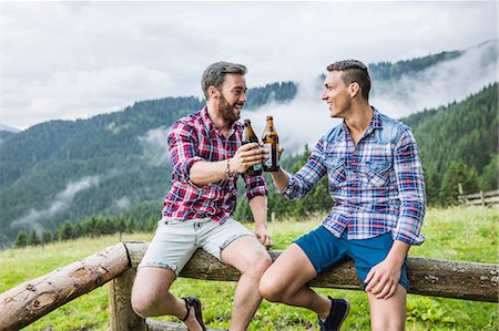 santé! - Two male friends drinking beer on fence, Tyrol Austria Photographie de stock - Premium Libres de Droits, Code: 649-07437131