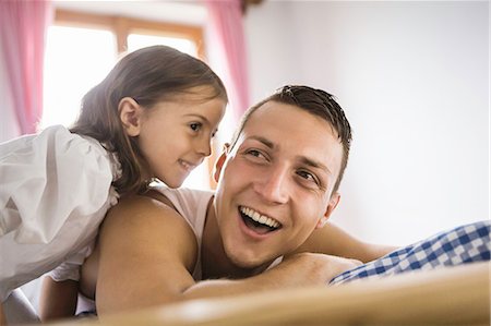 Young man and daughter on bed in holiday chalet, Tyrol, Austria Stock Photo - Premium Royalty-Free, Code: 649-07437148