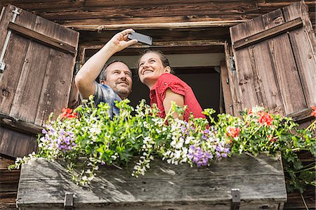 Couple taking self portrait from chalet window, Achenkirch,  Tyrol, Austria Stock Photo - Premium Royalty-Free, Code: 649-07437141