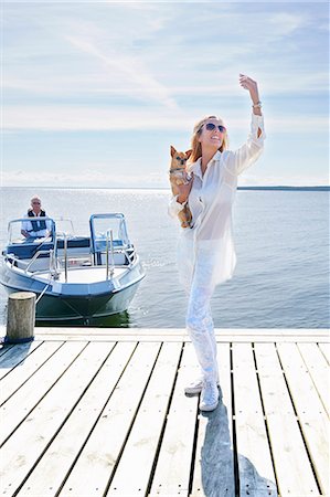 Young woman photographing herself with dog on pier, Gavle, Sweden Stock Photo - Premium Royalty-Free, Code: 649-07437170