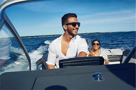 fun animals - Young man steering boat with woman in background, Gavle, Sweden Stock Photo - Premium Royalty-Free, Code: 649-07437180