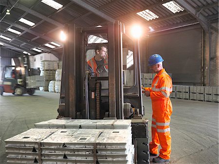Worker checking delivery of metal alloy with fork lift driver in port store Stock Photo - Premium Royalty-Free, Code: 649-07437258