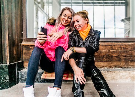 simsearch:640-06050812,k - Two female friends looking at mobile phone Fotografie stock - Premium Royalty-Free, Codice: 649-07437294