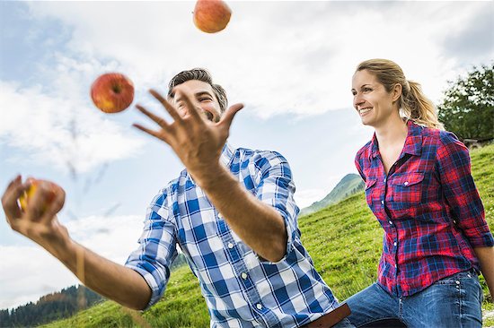 Woman looking at man juggling apples Stock Photo - Premium Royalty-Free, Image code: 649-07437333