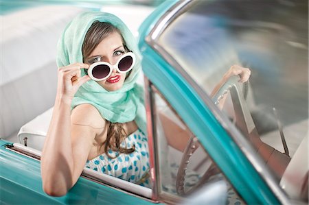 Woman in headscarf lowering sunglasses in vintage convertible Photographie de stock - Premium Libres de Droits, Code: 649-07437384