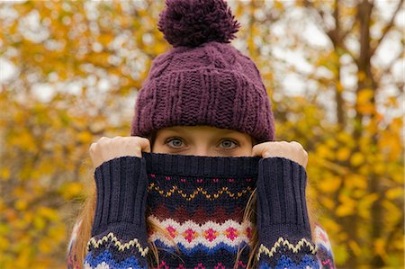 people hiding their face - Close up portrait of young woman in park with jumper hiding face Stock Photo - Premium Royalty-Free, Code: 649-07437641