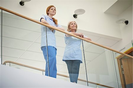 Two female nurses waiting on hospital atrium balcony Photographie de stock - Premium Libres de Droits, Code: 649-07437698