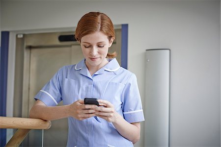 Female nurse looking at mobile phone outside hospital elevator Foto de stock - Sin royalties Premium, Código: 649-07437705