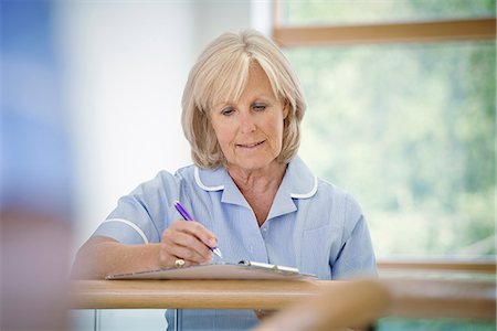 satisfied - Mature female nurse in hospital corridor with clipboard Stock Photo - Premium Royalty-Free, Code: 649-07437702