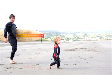 Father carrying surfboard with son on beach Stock Photo - Premium Royalty-Free, Code: 649-07437734