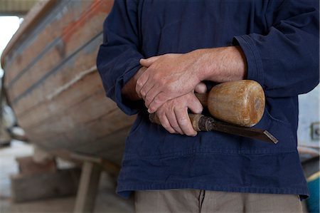 Close up of carpenters hands holding chisel in boat workshop Foto de stock - Sin royalties Premium, Código: 649-07437819