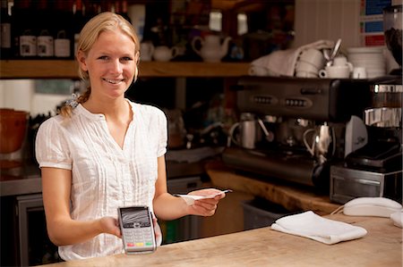 portraits of waiters - Portrait of young waitress holding credit card reader at kitchen counter Stock Photo - Premium Royalty-Free, Code: 649-07437824