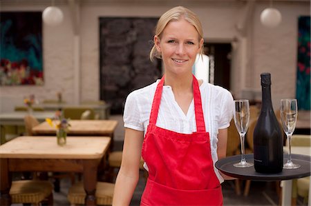 Portrait of waitress with tray of wine and glasses in cafe Stock Photo - Premium Royalty-Free, Code: 649-07437829