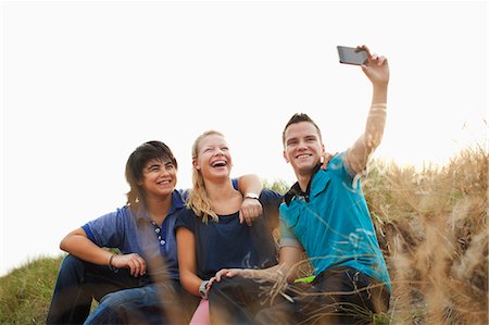 simsearch:649-06844580,k - Teenagers sitting on sand dune taking self portrait photograph Stock Photo - Premium Royalty-Free, Code: 649-07437876