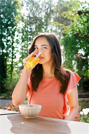 Portrait of young woman drinking orange juice in garden Stock Photo - Premium Royalty-Free, Code: 649-07437878