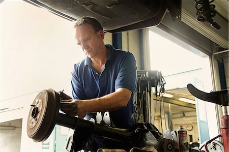 people working in car industry - Mechanic repairing car in workshop Stock Photo - Premium Royalty-Free, Code: 649-07438136