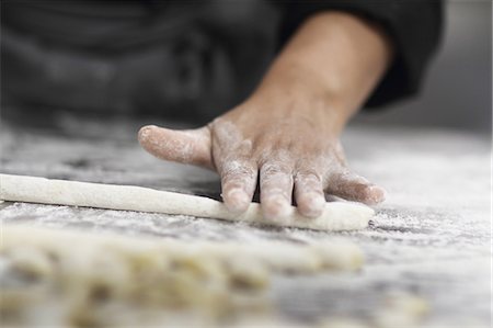 Woman working in restaurant kitchen, cropped hand rolling pastry Stock Photo - Premium Royalty-Free, Code: 649-07438138