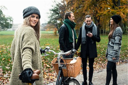 Young woman with bike, friends in background Stock Photo - Premium Royalty-Free, Code: 649-07520100