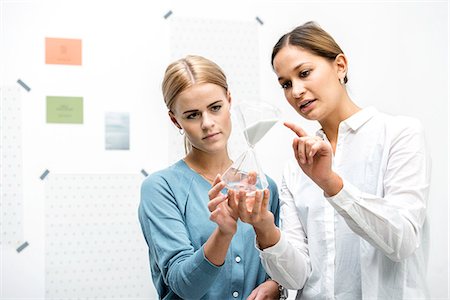 Female colleagues discussing workings of the hourglass Stock Photo - Premium Royalty-Free, Code: 649-07520123