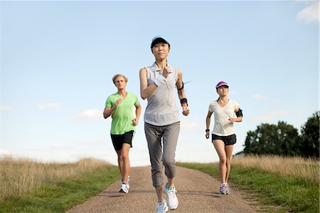 persona que trota - Three young adults jogging along field track Foto de stock - Sin royalties Premium, Código: 649-07520229
