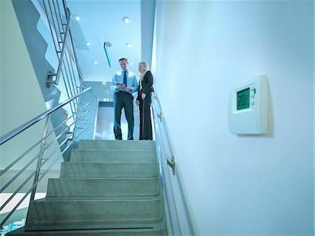 View of thermostat in office stairwell with workers in meeting on stairs Stockbilder - Premium RF Lizenzfrei, Bildnummer: 649-07520351