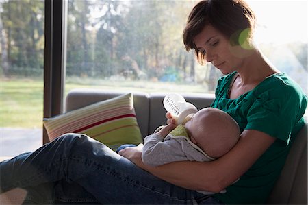 family inside a home - Mother feeding bottle to baby boy on sofa Foto de stock - Sin royalties Premium, Código: 649-07520607