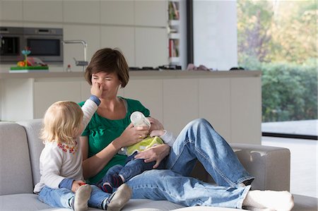 Mother, baby boy and female toddler sitting on sofa Fotografie stock - Premium Royalty-Free, Codice: 649-07520608