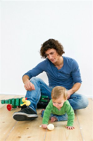 rattling - Studio shot of father and baby daughter paying on floor Stock Photo - Premium Royalty-Free, Code: 649-07520664