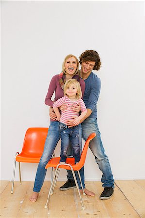 Studio shot of couple with young daughter standing on chair Stock Photo - Premium Royalty-Free, Code: 649-07520674