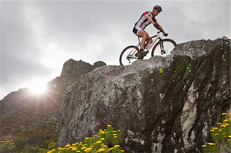 Young man mountain biking on top of rock formation Foto de stock - Sin royalties Premium, Código: 649-07520855