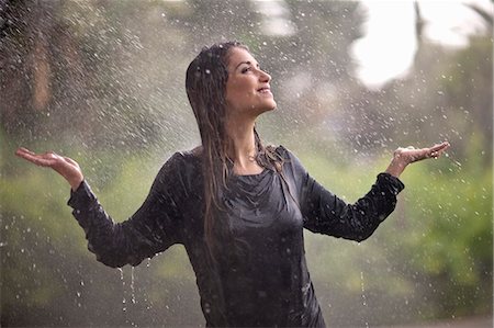 saturated - Drenched young woman with arms open in rainy park Stock Photo - Premium Royalty-Free, Code: 649-07520867