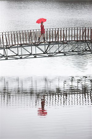 Young woman in red crossing footbridge in rain Photographie de stock - Premium Libres de Droits, Code: 649-07520860