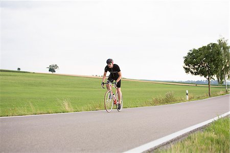 Mature man cycling along country road Stock Photo - Premium Royalty-Free, Code: 649-07520870