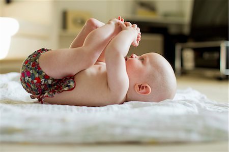 Baby girl lying on back playing with feet Photographie de stock - Premium Libres de Droits, Code: 649-07521023