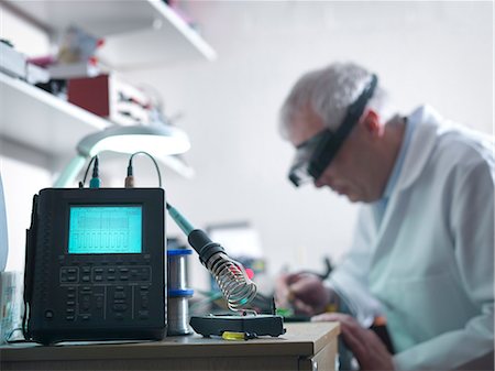 Engineer soldering prototype circuit board with oscilloscope in foreground Stock Photo - Premium Royalty-Free, Code: 649-07521174