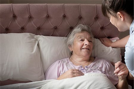 Personal care assistant chatting to senior woman in bed Stock Photo - Premium Royalty-Free, Code: 649-07521171