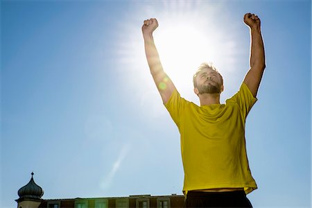 exercise and low angle - Young male athlete celebrating on city rooftop Stock Photo - Premium Royalty-Free, Code: 649-07559759